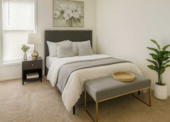 A bedroom with a large bed and a small bench in front of it.