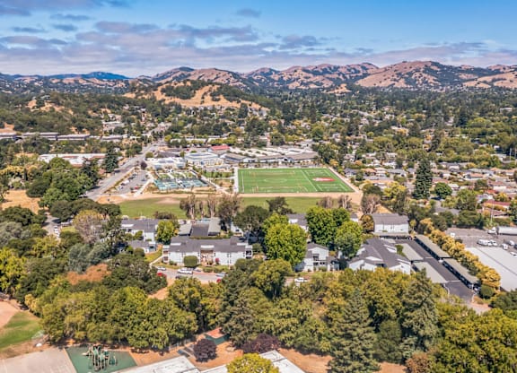 A bird's eye view of a residential area with a large green field and a football field.
