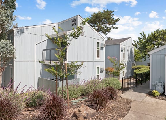 A modern building with a grey exterior and a garden in front.