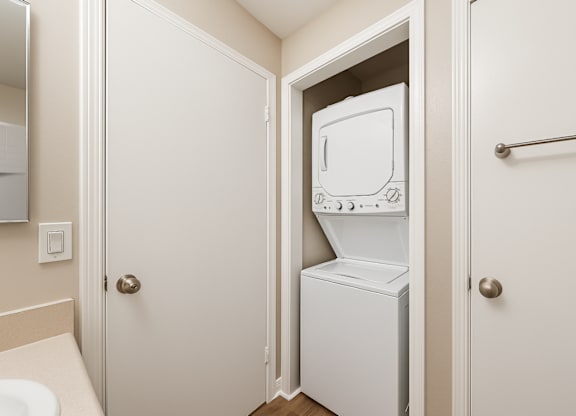 A white refrigerator is in a small bathroom.
