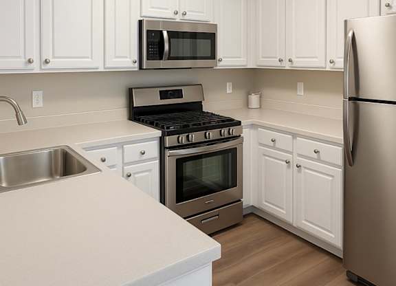 A kitchen with white cabinets and a stainless steel refrigerator.