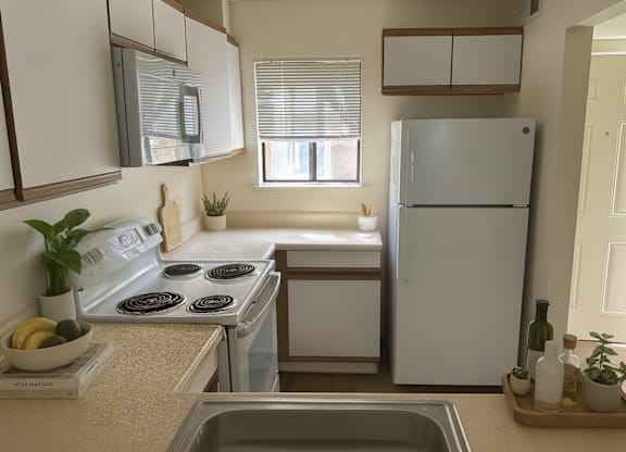 A kitchen with a stove, refrigerator, and sink.