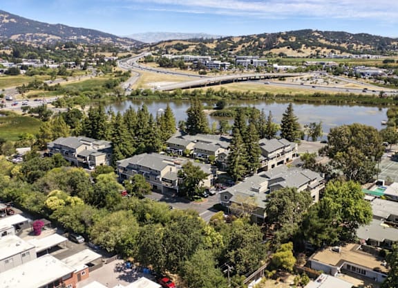 A bird's eye view of a residential area with houses, trees, and a river.