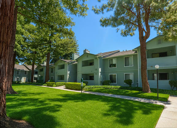 A sunny day at a residential area with apartment buildings and green trees.