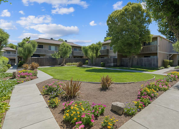 A sunny day at a residential area with apartment buildings and a flower garden.