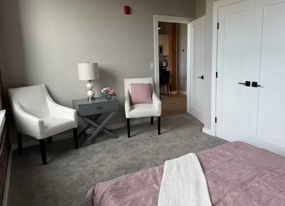 a bedroom with a bed and two chairs and a table