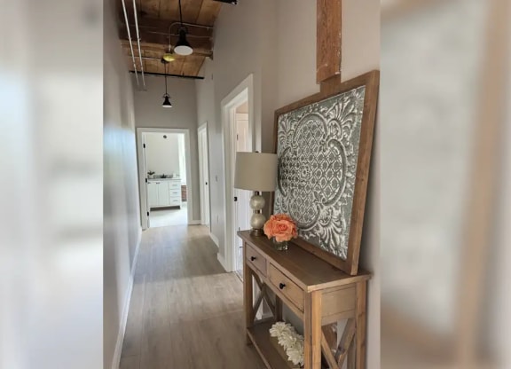 a hallway with a painting and a table with a lamp