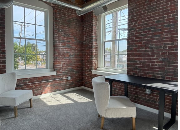 a room with two chairs and a desk and a brick wall