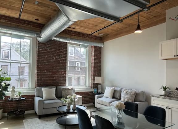 a living room with a couch and a table and a exposed brick wall
