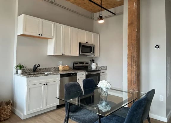 a kitchen with white cabinets and a glass table