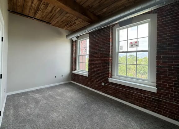 an empty room with a brick wall and a window