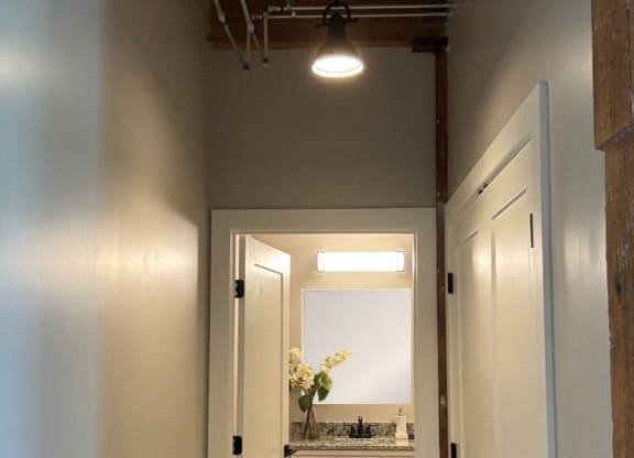 a view of a bathroom from the hallway with a sink and a mirror