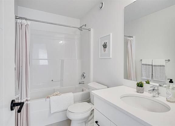 A white bathroom with a toilet, sink, and shower.