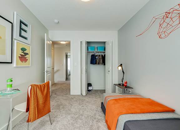 A bedroom with a bed, a chair, and a painting on the wall.