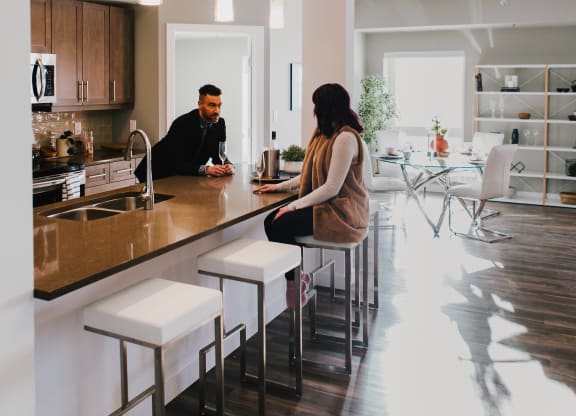 a man and woman sitting at a counter in a kitchen