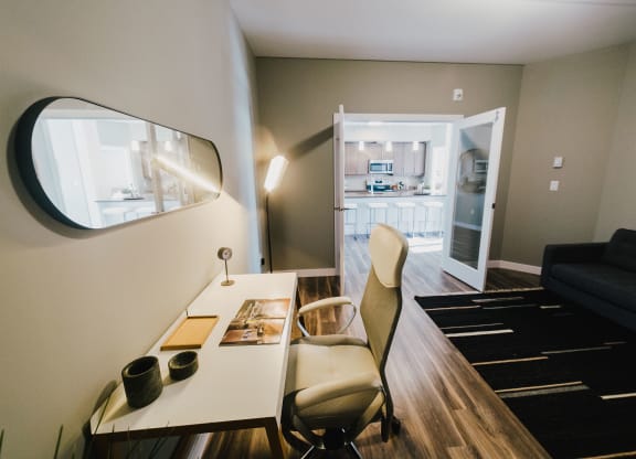 a small living room with a desk and a mirror