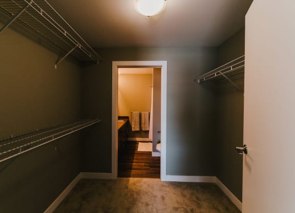 a walk in closet with a mirrored closet door and a door to a bathroom