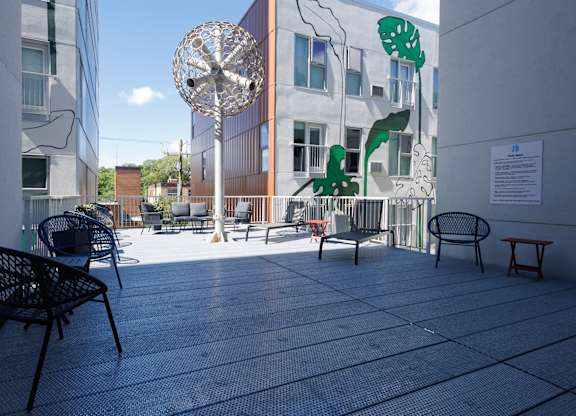 A patio with chairs and a table with a sign on the wall.