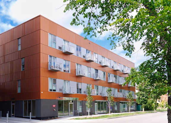 A modern building with orange and white panels and balconies.