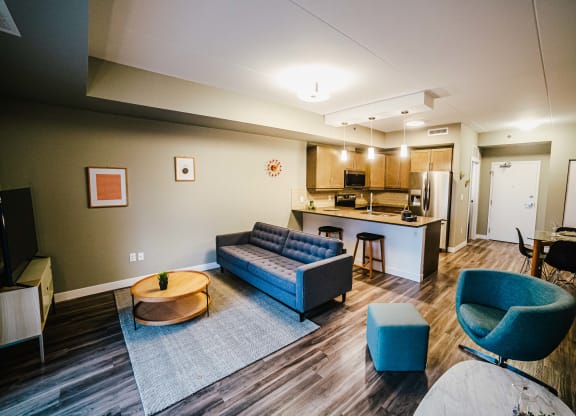 a living room with couches and chairs and a kitchen with a counter