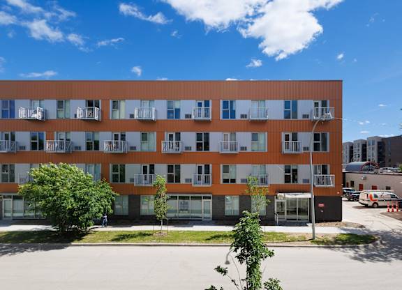 A large building with orange and white panels and balconies.