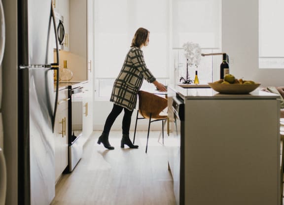 a woman in a kitchen with a table and a refrigerator