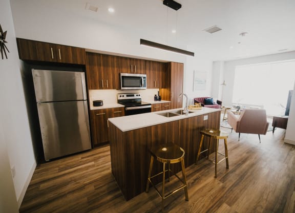 a kitchen and living room with wooden floors and a stainless steel refrigerator