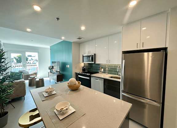 A modern kitchen with a stainless steel refrigerator and a dining table set with plates and bowls.