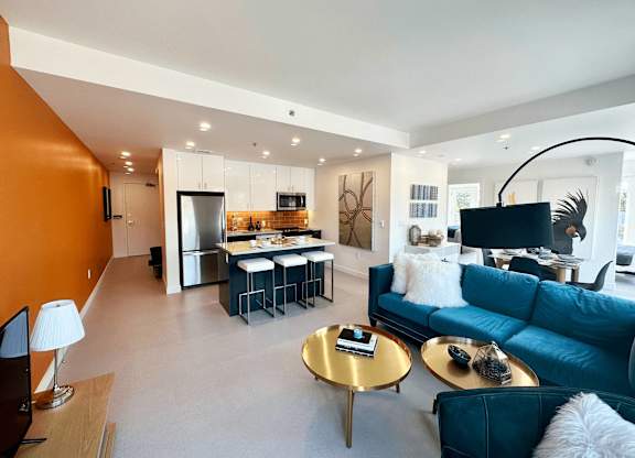 A modern living room with a blue couch and a gold coffee table.
