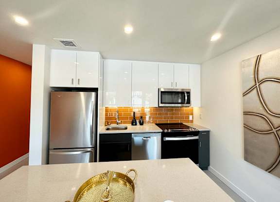 A kitchen with a refrigerator, microwave, oven, and sink.