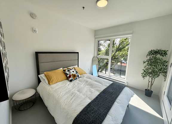A bedroom with a large bed and a window overlooking a tree.