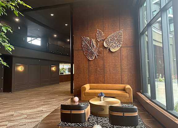 A room with a brown sofa and a wall decoration of butterflies.