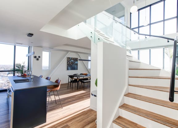 a living room with a staircase and a table and a kitchen