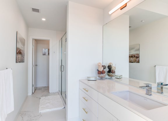 a white bathroom with a sink and a shower
