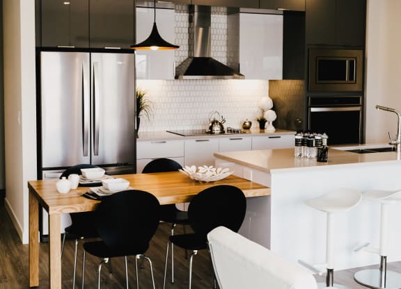 a kitchen and dining area with black and white appliances and a wooden table