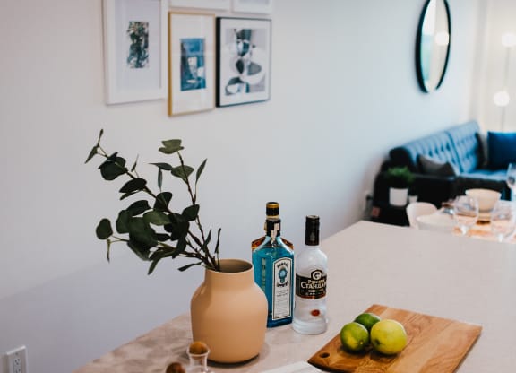 a kitchen counter with a cutting board with fruit and a bottle of wine on it