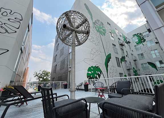 A patio with chairs and a table is in front of a building with graffiti on it.