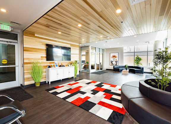 A modern office lobby with a wooden ceiling and a black and white rug.