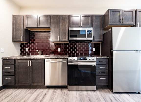 A kitchen with a stainless steel refrigerator, oven, and microwave.