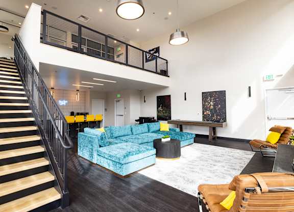 A living room with a staircase and a blue couch.