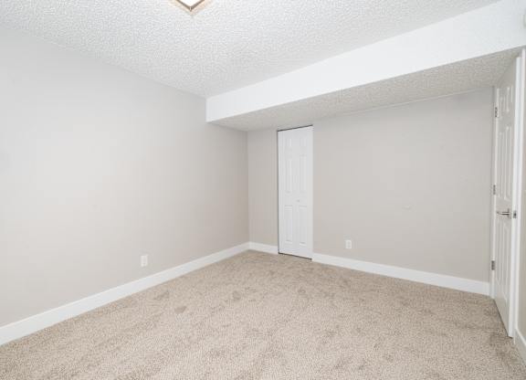 A room with a carpeted floor and a white door.