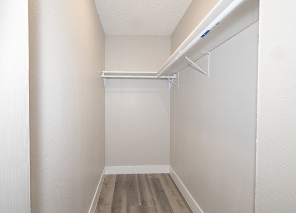 A small, empty room with a wooden floor and white walls.