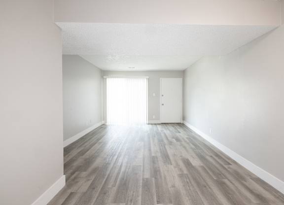 A room with light grey wooden flooring and white walls.