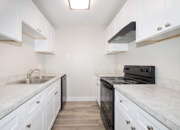 A kitchen with white cabinets and a black stove top oven.