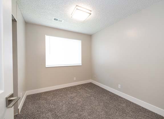A room with a carpeted floor and a window.
