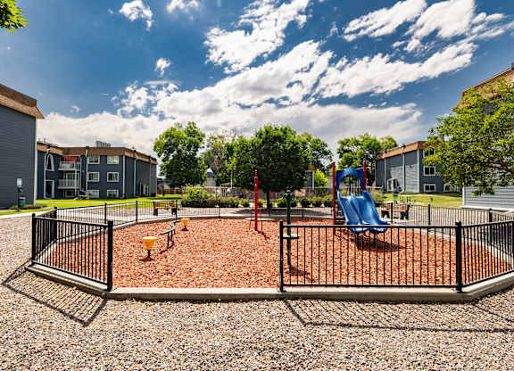 A playground with a swing set and a red slide.