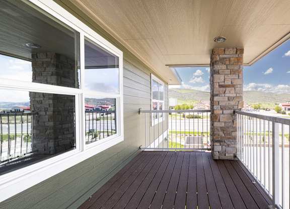 A balcony with a stone pillar and wooden floor.