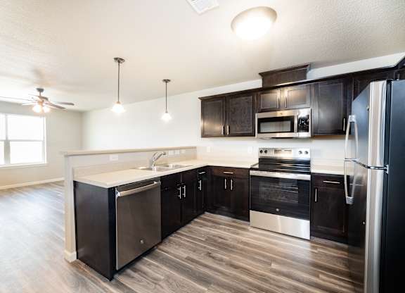 A modern kitchen with dark wood cabinets and stainless steel appliances.