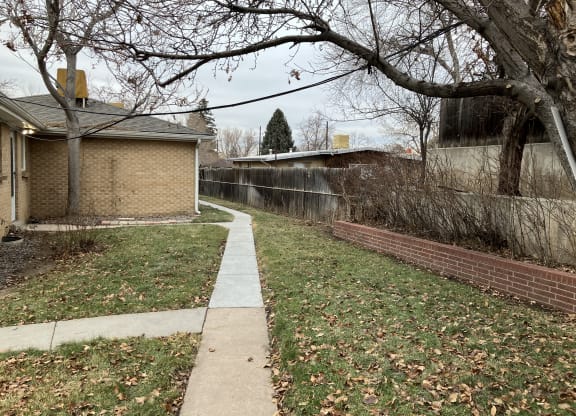 a sidewalk in front of a house with a tree