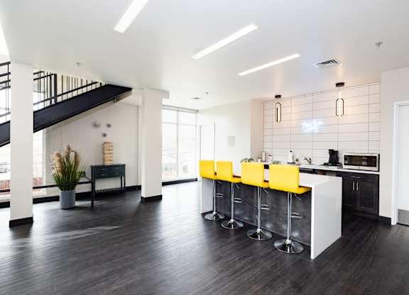 a kitchen with a bar and yellow chairs